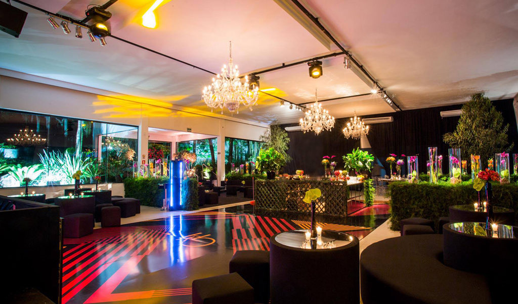 Pista de dança em vermelho e preto, entre lounges e jardim